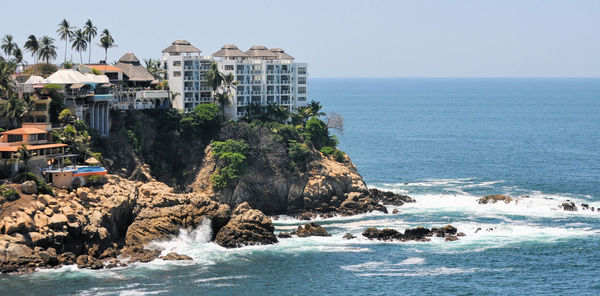 Scenic view of sea and buildings against clear sky