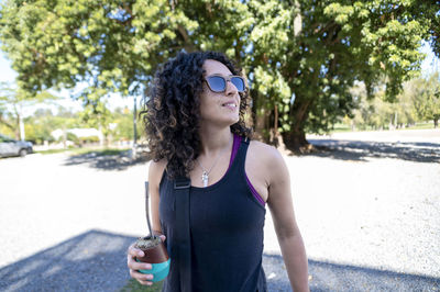 Portrait of young woman standing against trees