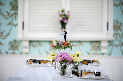 Flower vase on table against white wall