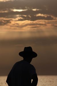 Rear view of silhouette man at beach during sunset