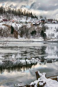 Scenic view of frozen lake by building against sky