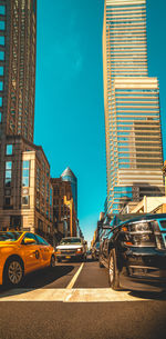 Cars on road in city against blue sky