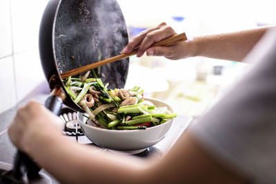 Midsection of person having food in kitchen