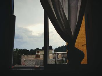 Silhouette man looking through window