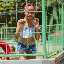 Portrait of smiling young woman looking through fence