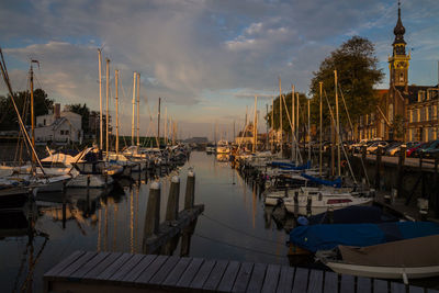 Boats moored at harbor against sky