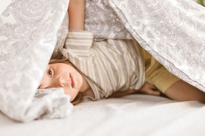 An adorable boy, toddler, plays on the parents' bed. sits wrapped in a blanket and laughs. family