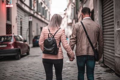 Rear view of people walking on street in city