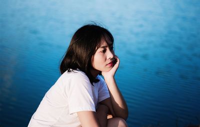 Thoughtful woman sitting by sea