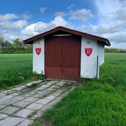 Information sign on field by building against sky