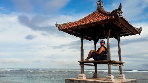 Women sitting by sea against sky