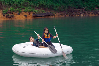Cute girl and boy sitting on boat in lake