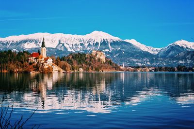 Scenic view of lake by mountains against clear blue sky