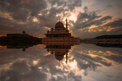 Reflection of temple in city against cloudy sky