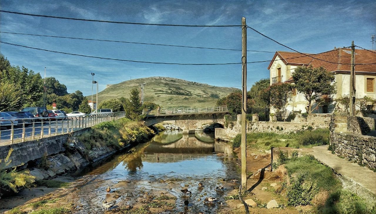 BRIDGE OVER CANAL BY BUILDING AGAINST SKY