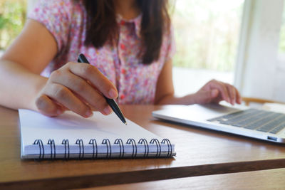 Midsection of woman using mobile phone on table