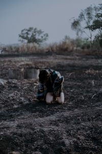 Rear view of woman sitting on land against sky