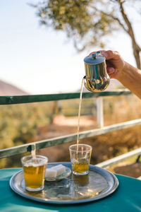 Cropped hand pouring tea in cup at table