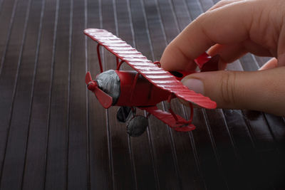 Cropped hand holding toy airplane on table