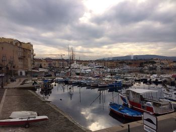 Boats in harbor against cloudy sky