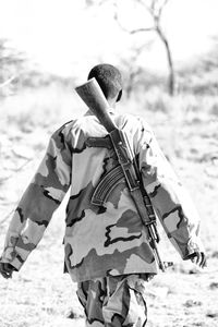 Rear view of man holding umbrella on land