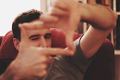 Portrait of young man making finger frame at home