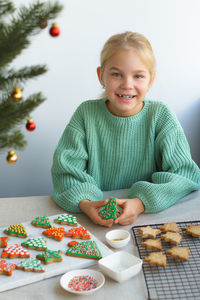 A cute girl prepares bright festive cookies for christmas and new year.