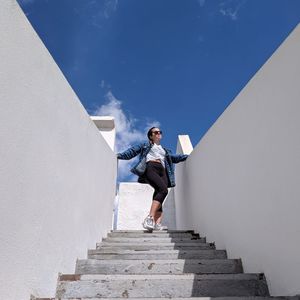 Low angle view of woman standing on staircase against sky