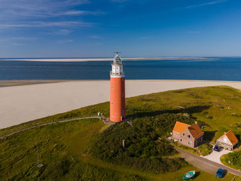 Lighthouse by sea against sky