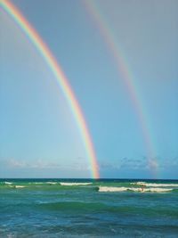 Scenic view of rainbow over sea against sky