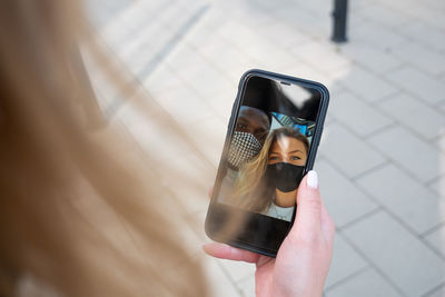 Cropped hand of woman holding smart phone outdoors