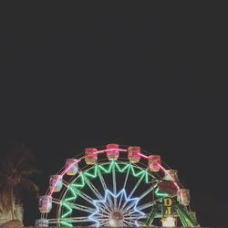 Illuminated ferris wheel against clear sky at night