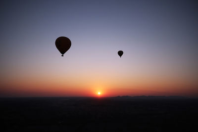 Silhouette hot air balloons against sky during sunset