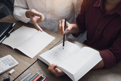Midsection of woman reading book on table