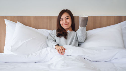 Portrait of young woman lying on bed at home