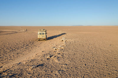 Vintage offroad car driving through empty namib desert of angola, africa