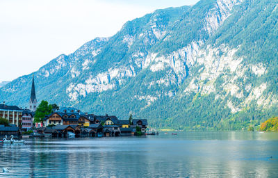 Scenic view of lake by buildings and mountains against sky