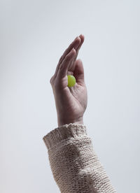 Close-up of hand holding grape against white background