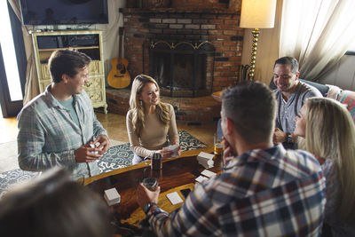 Happy friends enjoying card game during social gathering at home