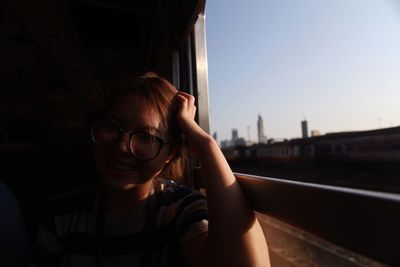 Portrait of young woman sitting in bus against clear sky during sunset