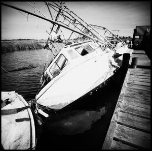 Fishing boat moored on pier by sea against sky