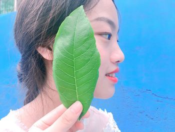 Close-up portrait of a beautiful young woman against blue sky