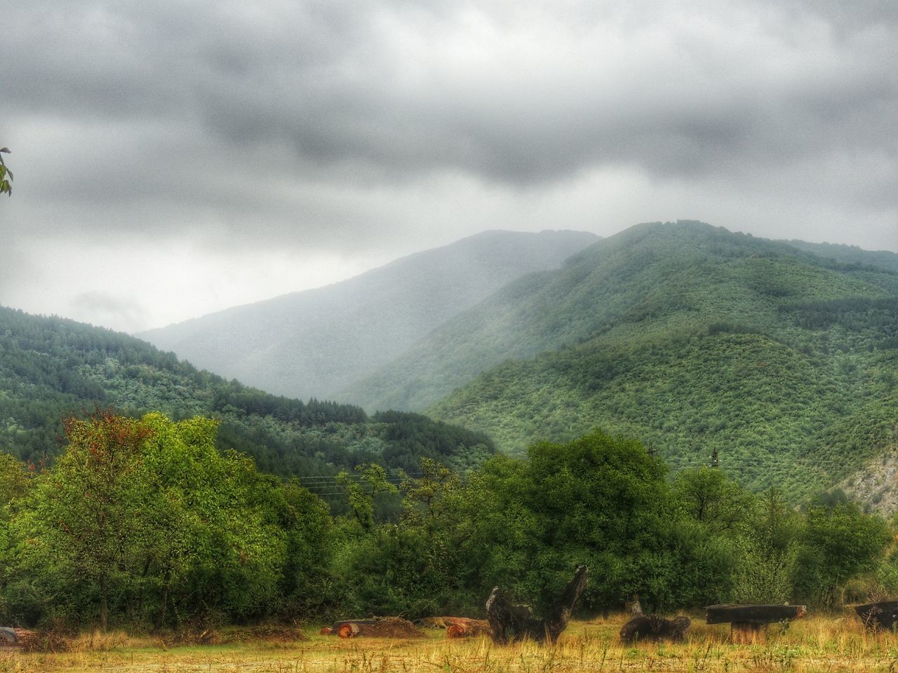 mountain, sky, tranquil scene, tranquility, scenics, mountain range, landscape, beauty in nature, cloud - sky, cloudy, nature, non-urban scene, tree, weather, cloud, green color, idyllic, growth, overcast, hill