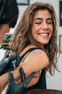 Close-up of mam making tattoo on woman back