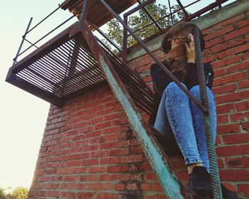 Low angle view of girl against brick wall