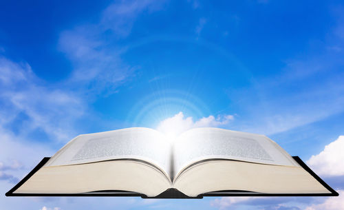 Low angle view of book against blue sky