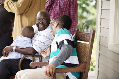 Happy senior man sitting with grandsons at porch