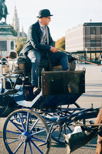 Full length of man sitting on street in city