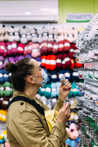 Woman in face mask selects beads products in handicraft store. shopping concept