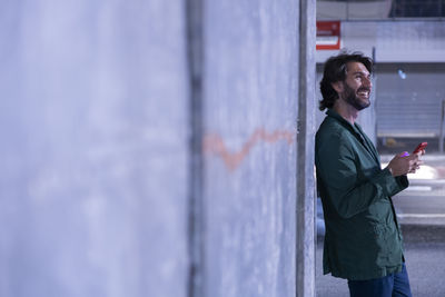 Portrait of young man standing against wall